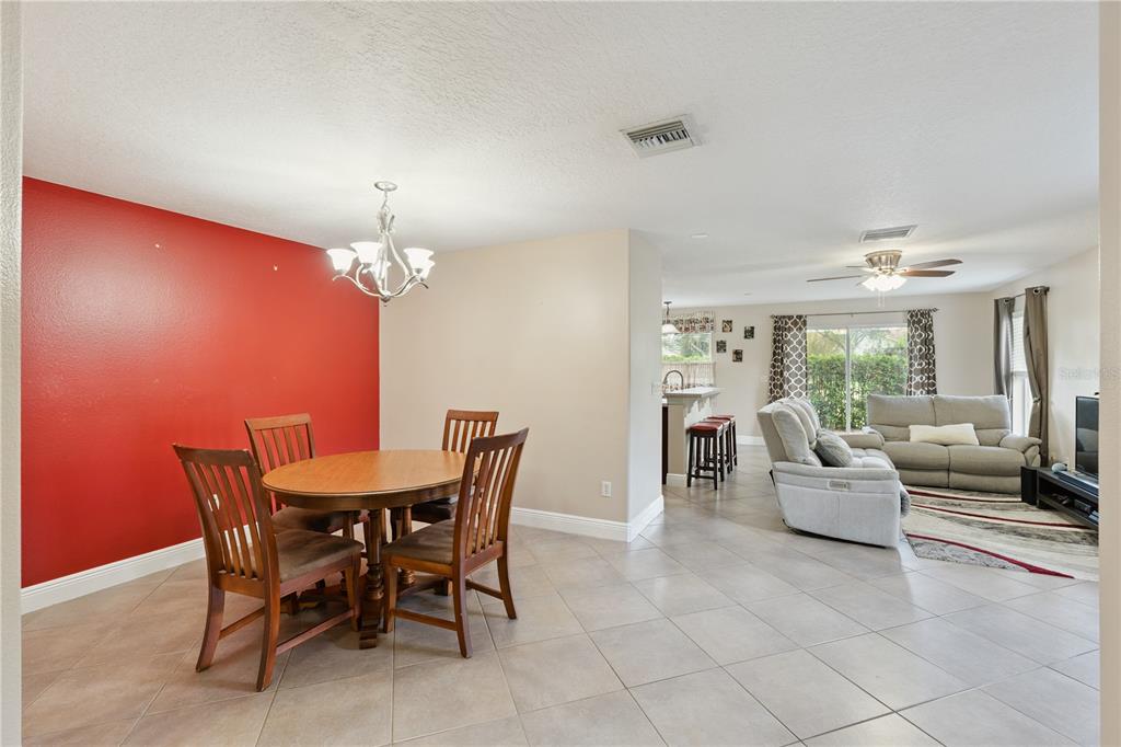 A dining area with a red accent wall opens into a living room with tile flooring — 3527 CARUSO PLACE, OVIEDO, FL
