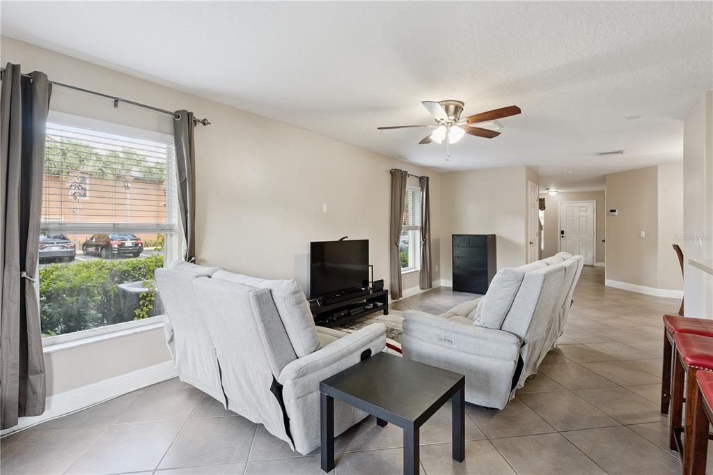 A living room with light-colored sofas, a television, tile flooring, and a ceiling fan — 3527 CARUSO PLACE, OVIEDO, FL