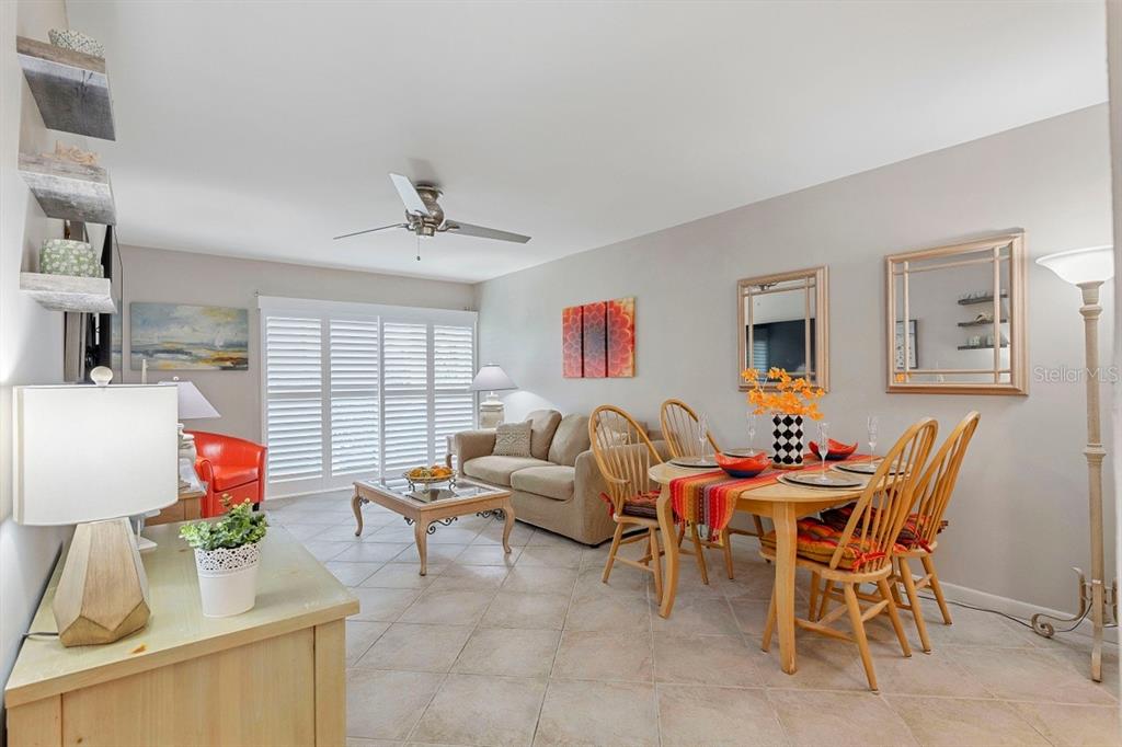 A living and dining area features tile floors, a ceiling fan, and neutral wall paint — 10365 PARADISE BOULEVARD UNIT 21, TREASURE ISLAND, FL