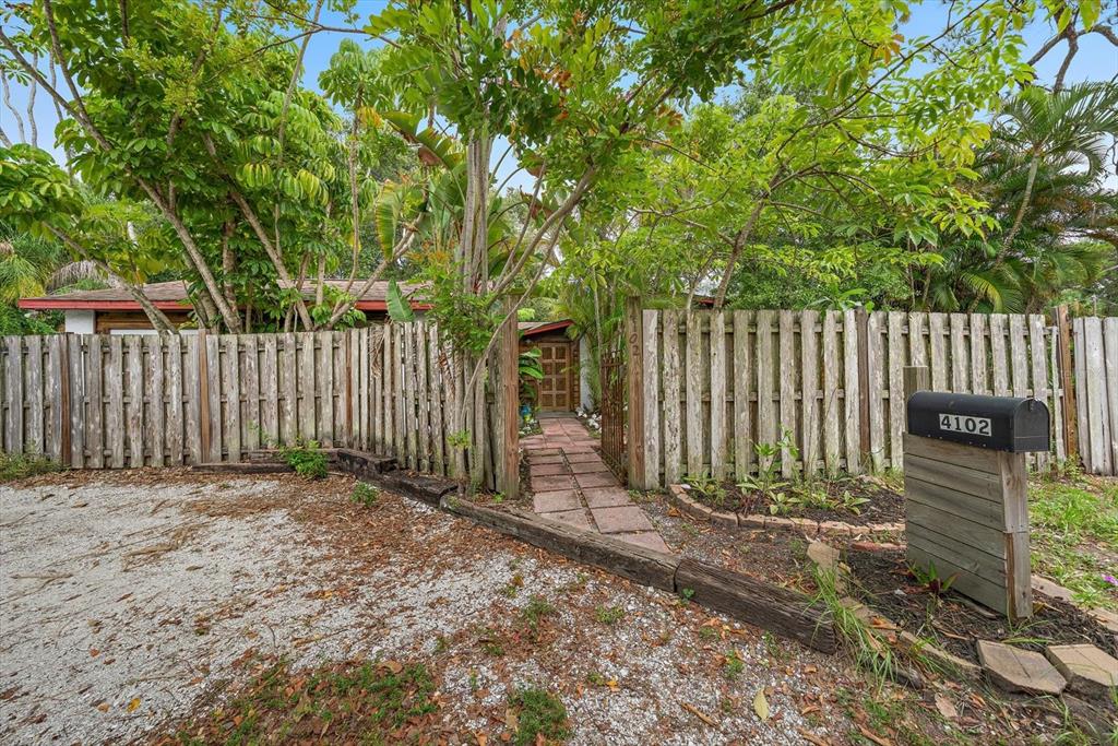 A gravel driveway leads to a wooden fence and a gated walkway entrance to a home — 4102 ROYAL PALM AVENUE, SARASOTA, FL