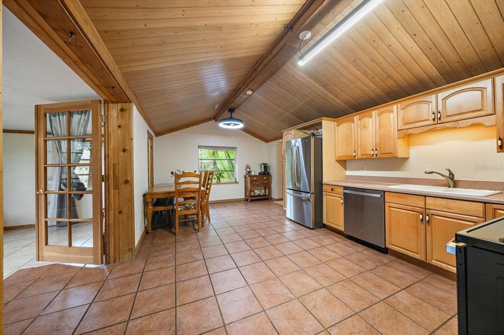 A kitchen and dining area with wood-paneled vaulted ceilings, tile flooring, and light wood cabinets — 4102 ROYAL PALM AVENUE, SARASOTA, FL