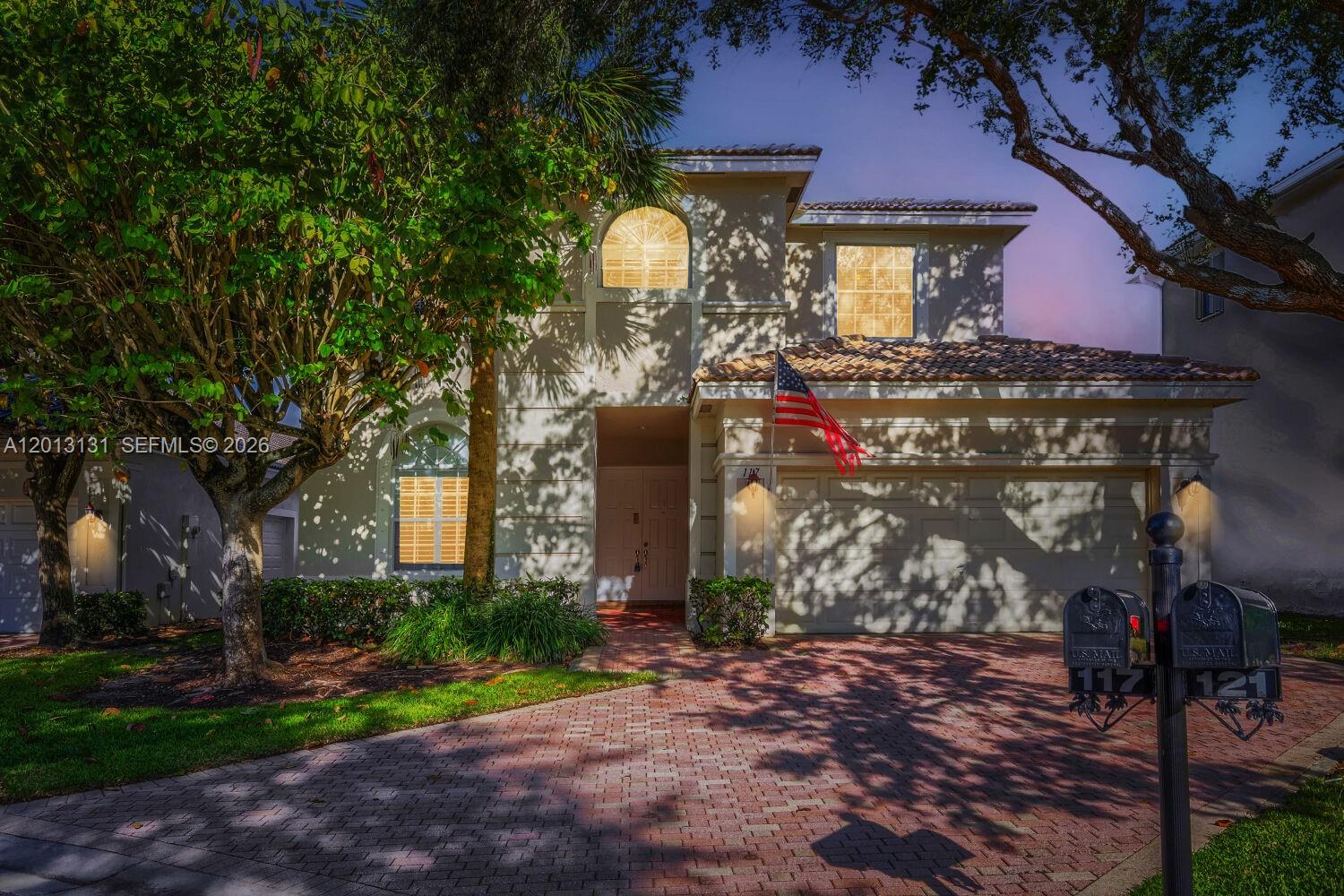 A two-story house with a brick driveway, a garage, and an American flag — 117 Palm Cir, Atlantis FL 33462, ATLANTIS, FL