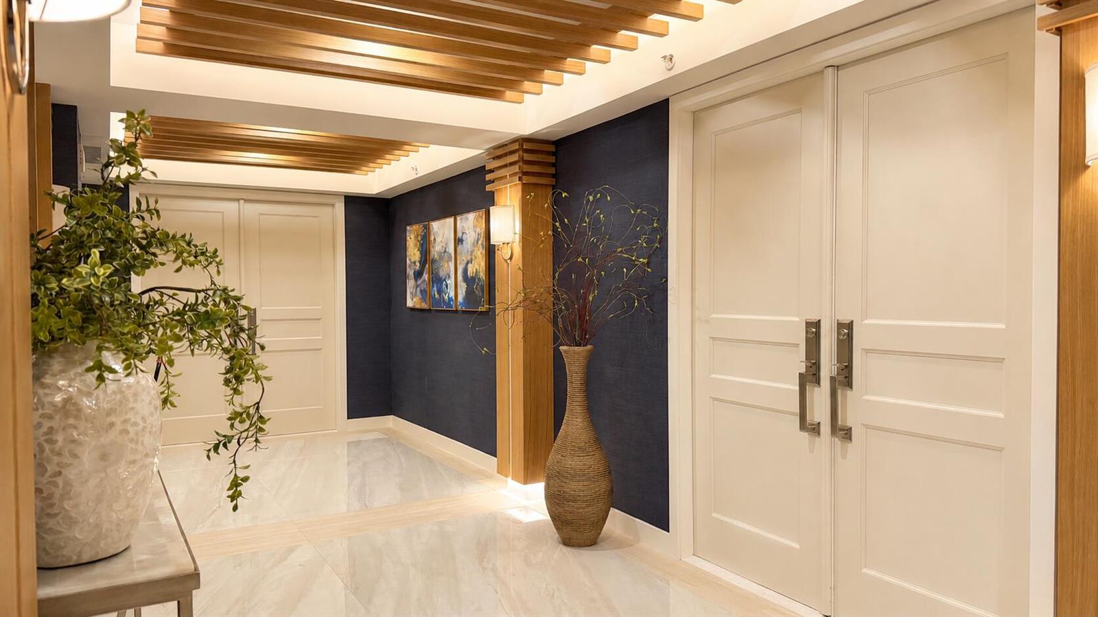 A modern hallway features white double doors, a dark blue accent wall, and wood-slat ceilings — 3000 S Ocean Boulevard # 1404, Boca Raton FL 33432, BOCA RATON, FL