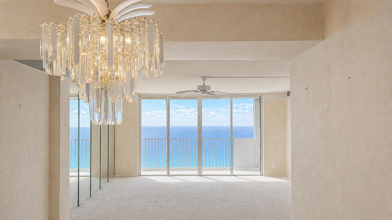 A room with beige carpet, a crystal chandelier, mirrored walls, and a view of the ocean — 3000 S Ocean Boulevard # 1404, Boca Raton FL 33432, BOCA RATON, FL