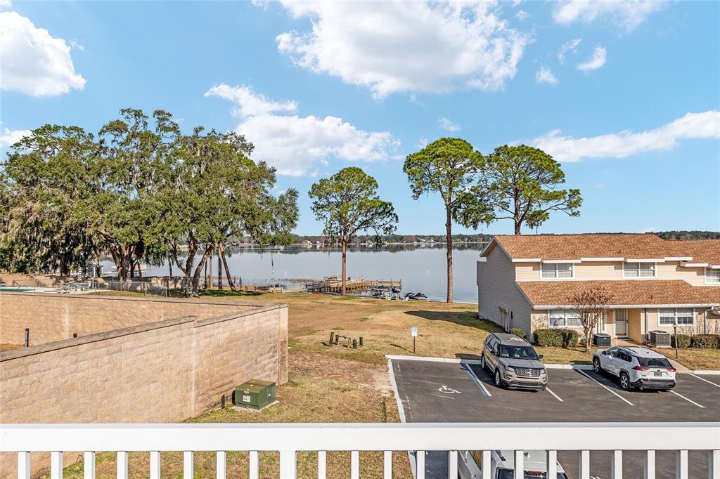 An elevated view of a parking lot, a grassy yard, and a lake with docks — 11001 SE SUNSET HARBOR ROAD UNIT D18, SUMMERFIELD, FL