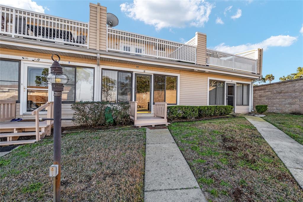 A row of tan townhouses with small wooden porches and second-story balconies — 11001 SE SUNSET HARBOR ROAD UNIT D18, SUMMERFIELD, FL