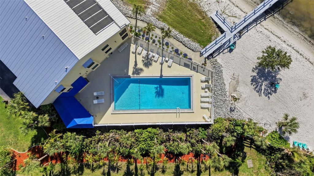 An aerial view shows a rectangular swimming pool next to a building with a pier — 14459 RIVER BEACH DRIVE UNIT B 110, PORT CHARLOTTE, FL