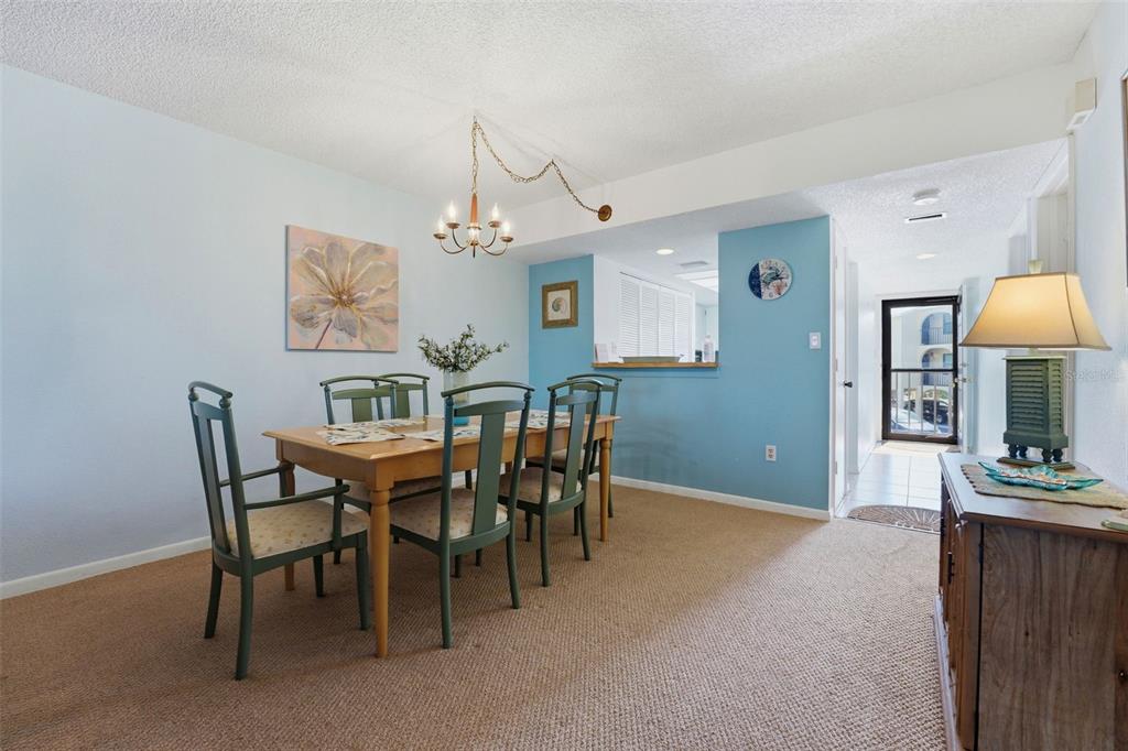 A dining room with a wooden table, green chairs, light blue walls, and carpeted flooring — 14459 RIVER BEACH DRIVE UNIT B 110, PORT CHARLOTTE, FL