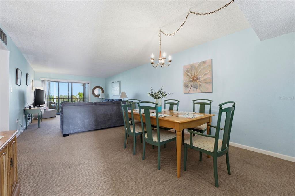 A dining area with a wooden table and green chairs sits beside a living room — 14459 RIVER BEACH DRIVE UNIT B 110, PORT CHARLOTTE, FL