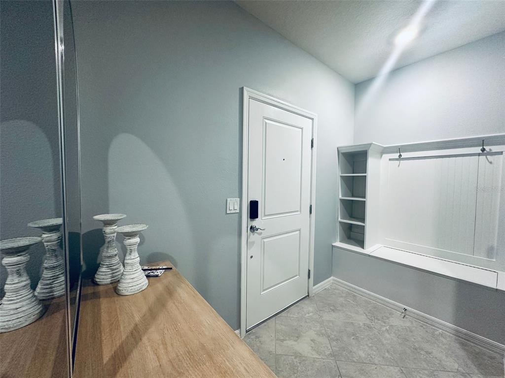 An entryway features a white door, a built-in bench with shelving, and a wooden console table — 1256 BLUE PARADISE DRIVE, CLERMONT, FL