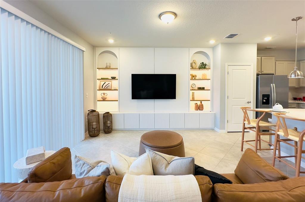 A living room features a large white built-in media wall with arched shelving and cabinets — 1256 BLUE PARADISE DRIVE, CLERMONT, FL