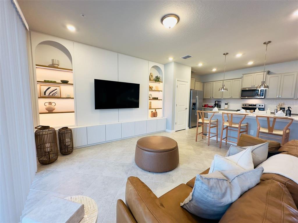 A living room features a built-in media wall with arched shelving and an open kitchen — 1256 BLUE PARADISE DRIVE, CLERMONT, FL