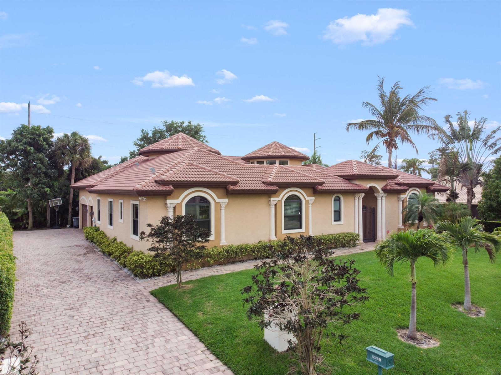 A single-story tan house with a tiled roof, arched windows, and a paved driveway — 4190 Gleneagles Drive, Boynton Beach FL 33436, BOYNTON BEACH, FL