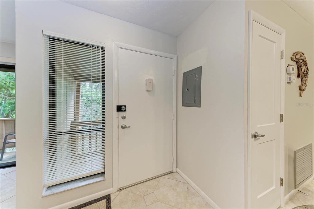 An entryway features a white front door, a window with blinds, and a breaker panel — 1709 CLOWER CREEK DRIVE UNIT 205, SARASOTA, FL