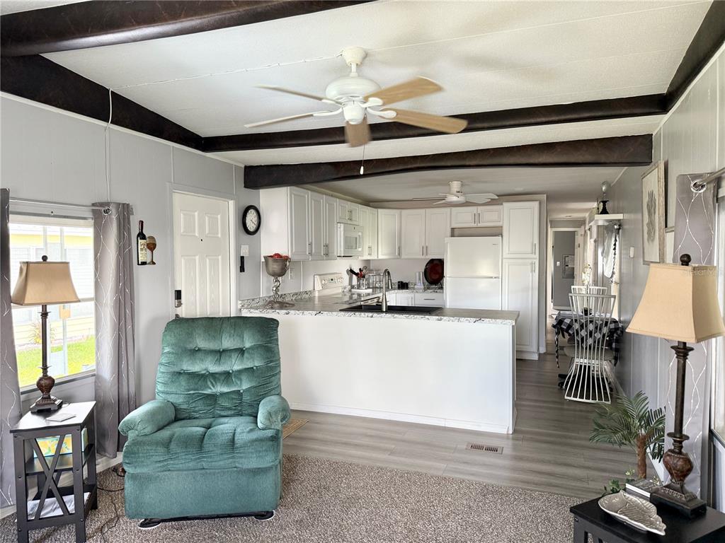 A living room with a green recliner opens to a kitchen featuring white cabinets — 34543 SWEETPEA LANE, ZEPHYRHILLS, FL