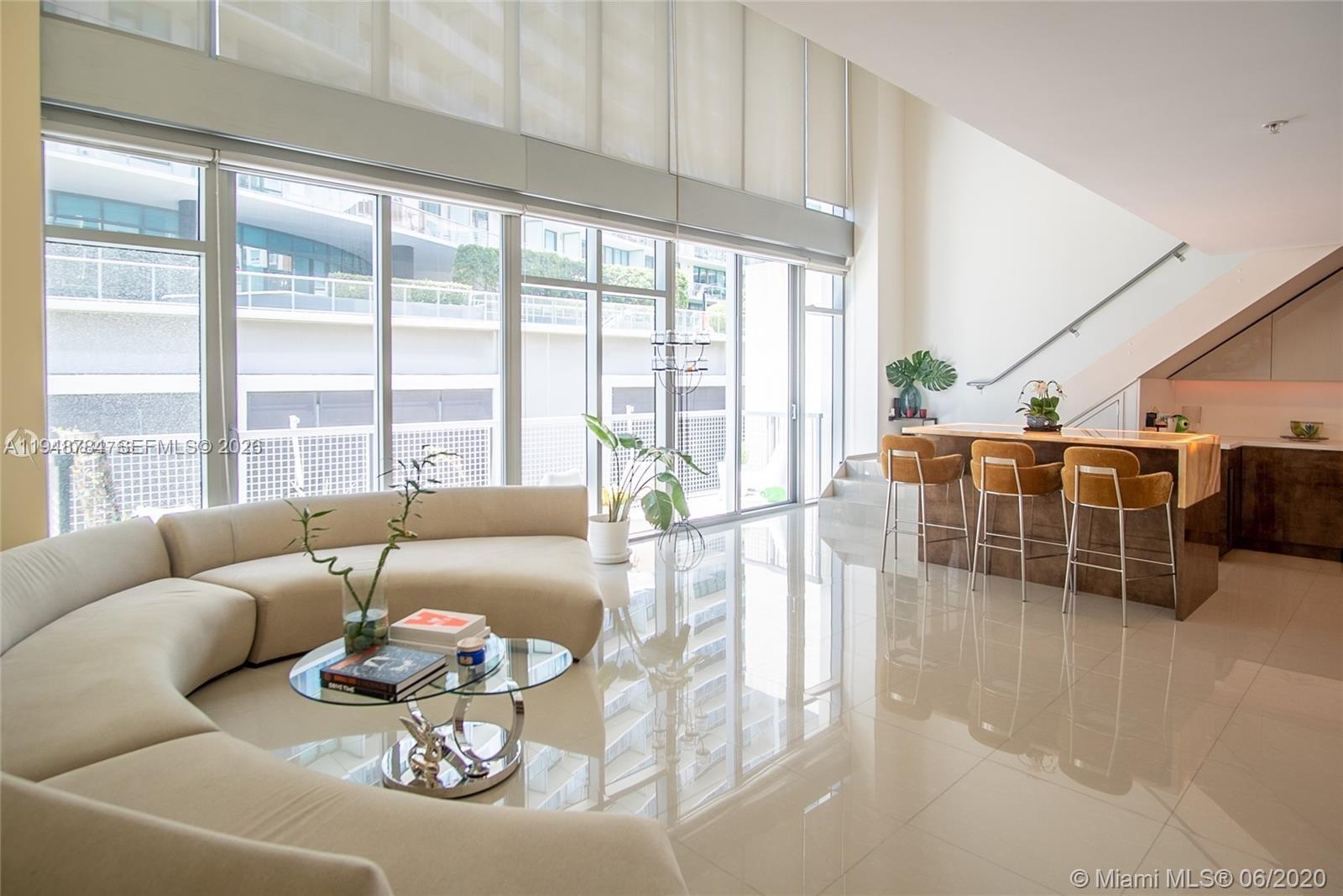 A modern living room features a curved sofa, a breakfast bar, and floor-to-ceiling windows — 3301 NE 1st Ave, Miami FL 33137, MIAMI, FL