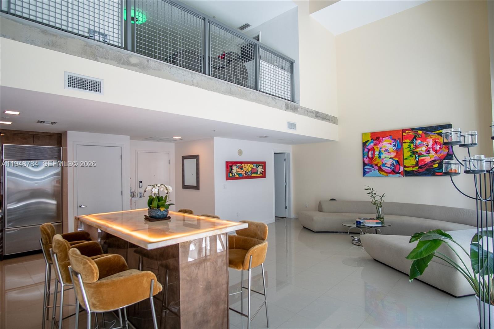 A modern living area features a kitchen island with glowing edges, yellow chairs, and artwork — 3301 NE 1st Ave, Miami FL 33137, MIAMI, FL
