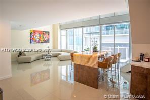 A modern living room features a curved white sofa, a stone-topped island, and floor-to-ceiling windows — 3301 NE 1st Ave, Miami FL 33137, MIAMI, FL