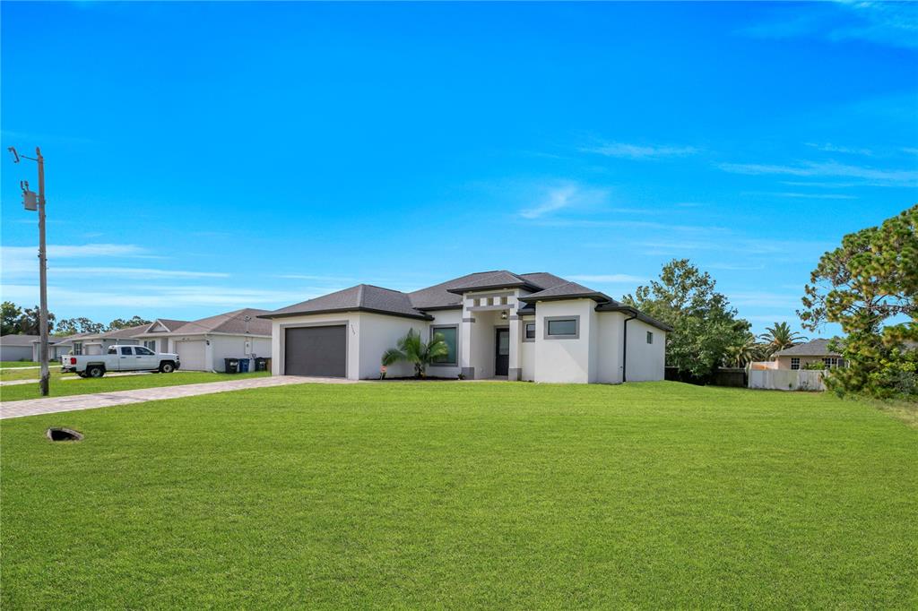 A single-story house with a white exterior, dark roof, and a large front lawn — 3509 38TH ST SW, LEHIGH ACRES, FL