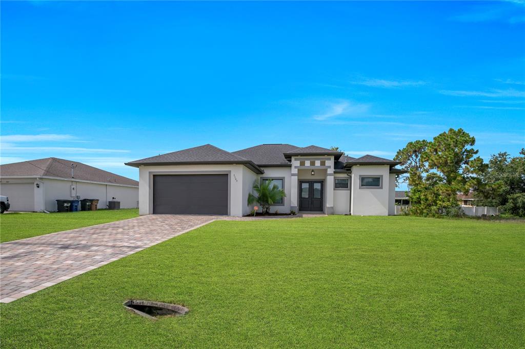 A single-story house with a gray garage, paved driveway, and a large front lawn — 3509 38TH ST SW, LEHIGH ACRES, FL