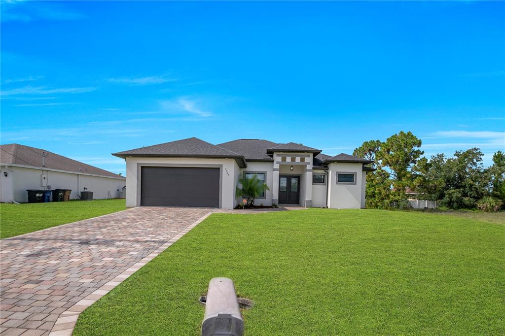 A single-story house with a paved driveway, a two-car garage, and a green lawn — 3509 38TH ST SW, LEHIGH ACRES, FL