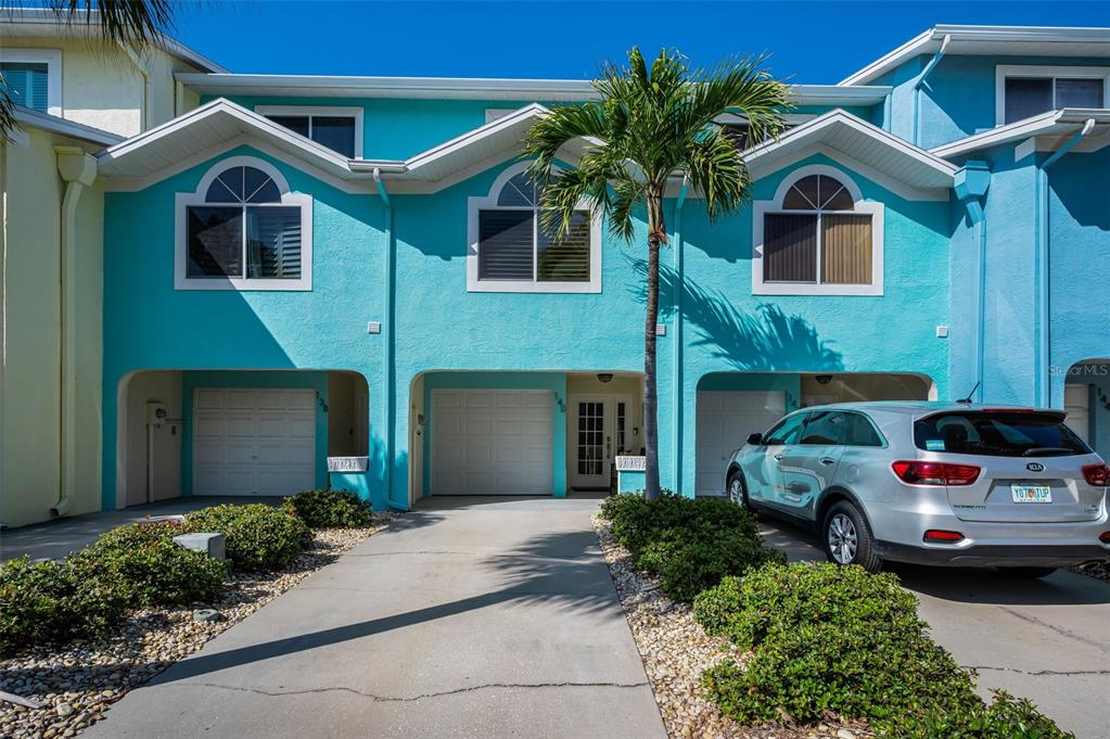 A row of three turquoise townhouses with garages and a palm tree in the front — 140 MARCDALE BOULEVARD, INDIAN ROCKS BEACH, FL