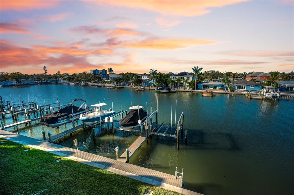 A canal view featuring several boats docked at wooden piers under a sunset sky — 140 MARCDALE BOULEVARD, INDIAN ROCKS BEACH, FL