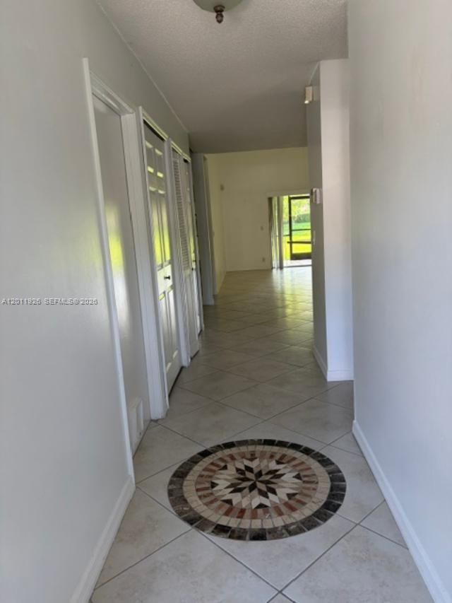 A tiled hallway features a decorative circular floor inlay and leads toward a living area — 667 Woodgate Ln # B, Sunrise FL 33326, SUNRISE, FL