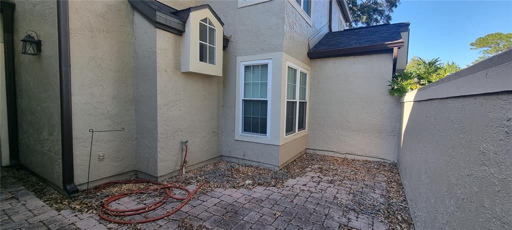 A paved patio area sits adjacent to a beige stucco house with a bay window — 1462 FARRINDON CIRCLE UNIT 1462, LAKE MARY, FL
