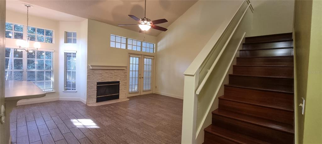 A living room with a fireplace, tile flooring, and a wooden staircase leading upstairs — 1462 FARRINDON CIRCLE UNIT 1462, LAKE MARY, FL