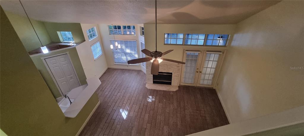 A high-angle view of a living room with wood-look tile floors, fireplace, and vaulted ceilings — 1462 FARRINDON CIRCLE UNIT 1462, LAKE MARY, FL