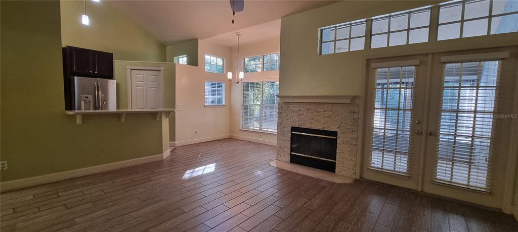 A living room features a stone fireplace, wood-look tile floors, and glass doors to a patio — 1462 FARRINDON CIRCLE UNIT 1462, LAKE MARY, FL