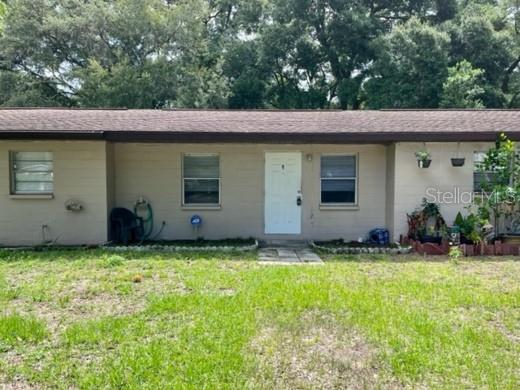 A single-story house with a beige block exterior, a brown roof, and a central white door — 12136 MUNBURY DRIVE UNIT 2, DADE CITY, FL
