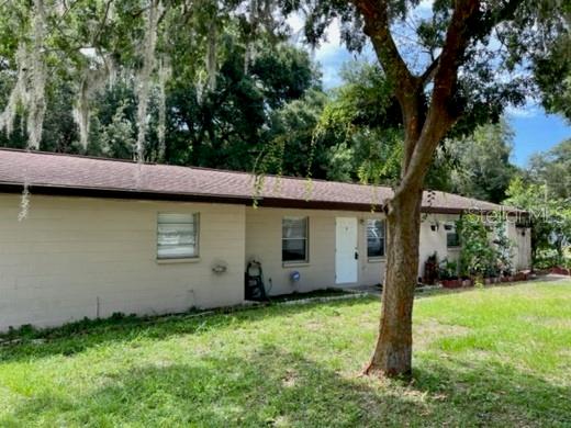 A single-story house with a tan exterior, a brown shingled roof, and a large tree — 12136 MUNBURY DRIVE UNIT 2, DADE CITY, FL