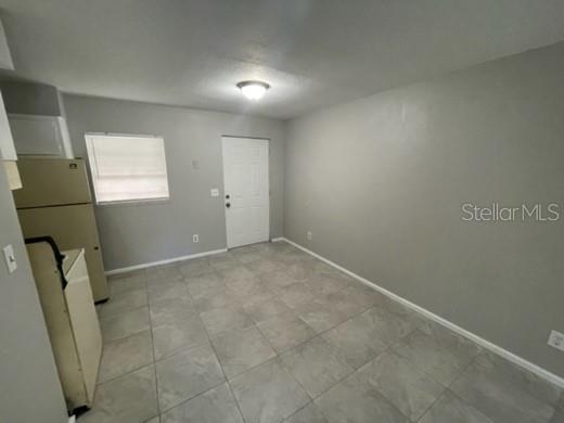 A kitchen with light gray walls, tile flooring, a white door, and a refrigerator — 12136 MUNBURY DRIVE UNIT 2, DADE CITY, FL