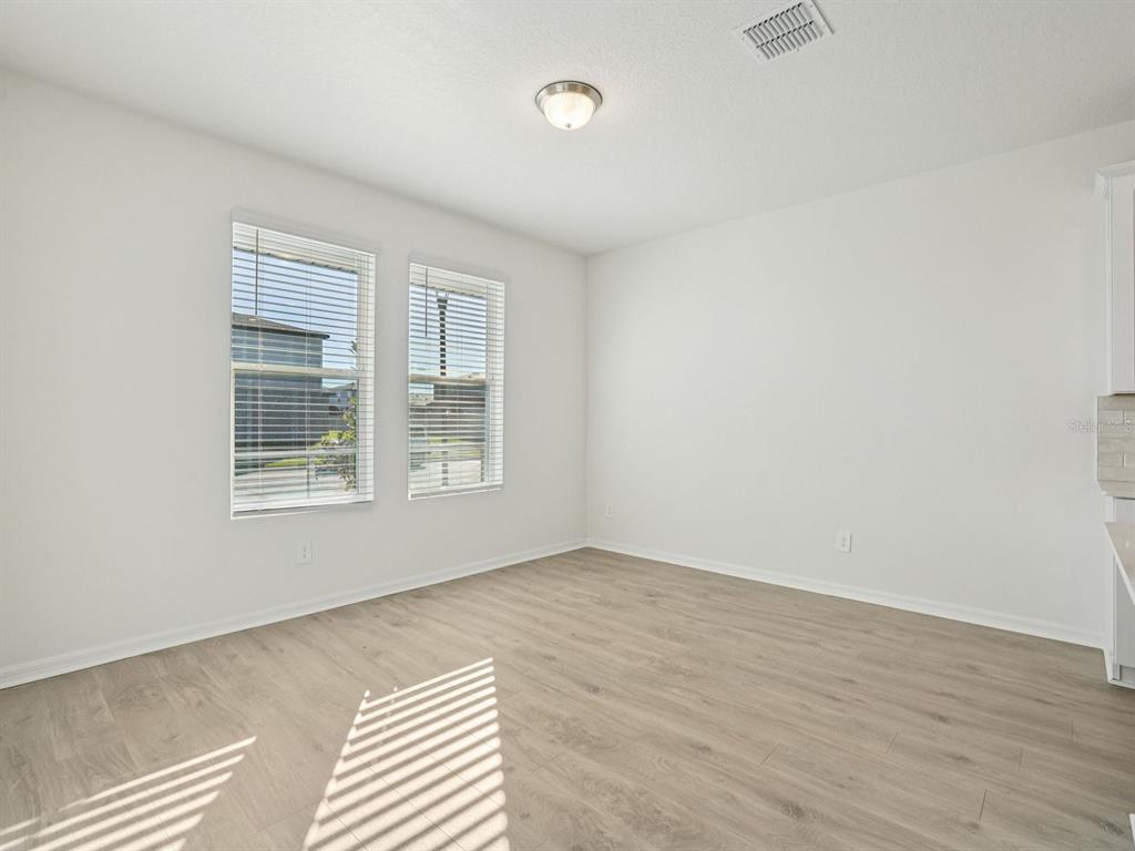 An empty room with light wood-look flooring, white walls, and two windows with blinds — 4689 CROSS PRAIRIE PARKWAY, ST CLOUD, FL