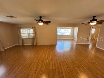 A spacious living area features light wood-look flooring, two ceiling fans, and a large window — 9759 SW 97TH LANE, OCALA, FL