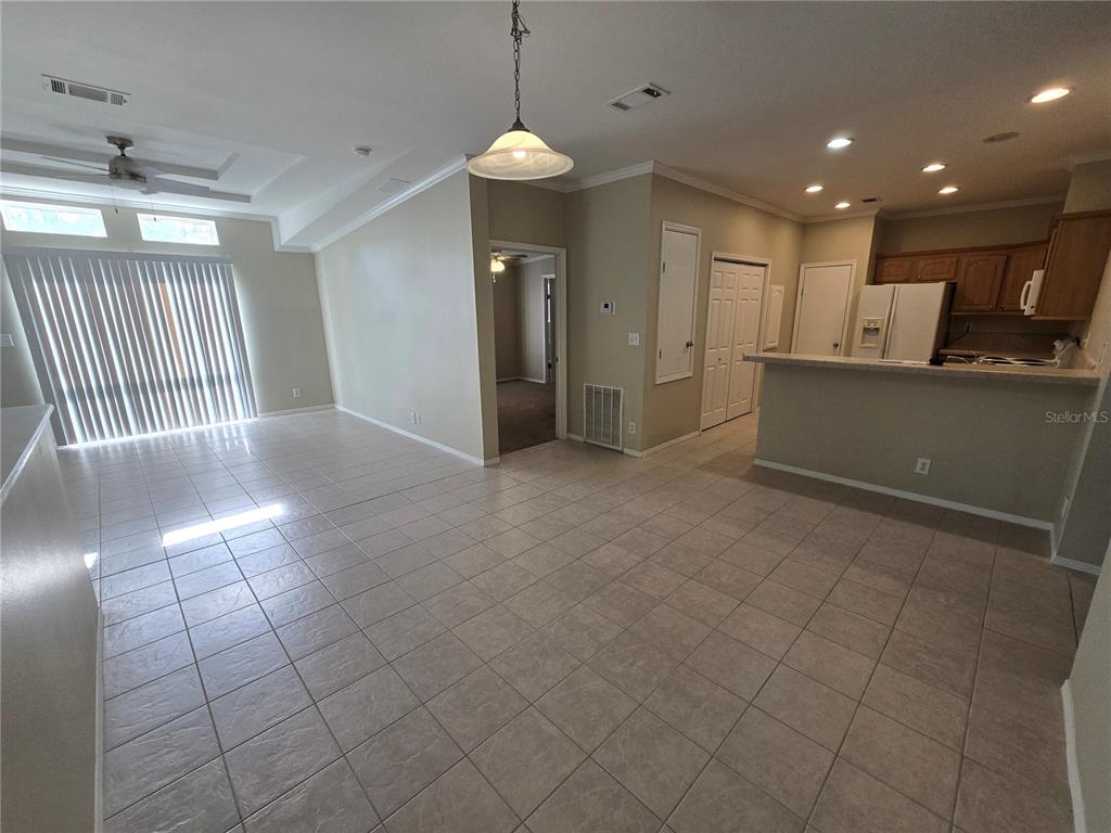 An open-concept living and dining area features tile flooring, a kitchen counter, and sliding doors — 7644 SAILWINDS PASS, PORT RICHEY, FL