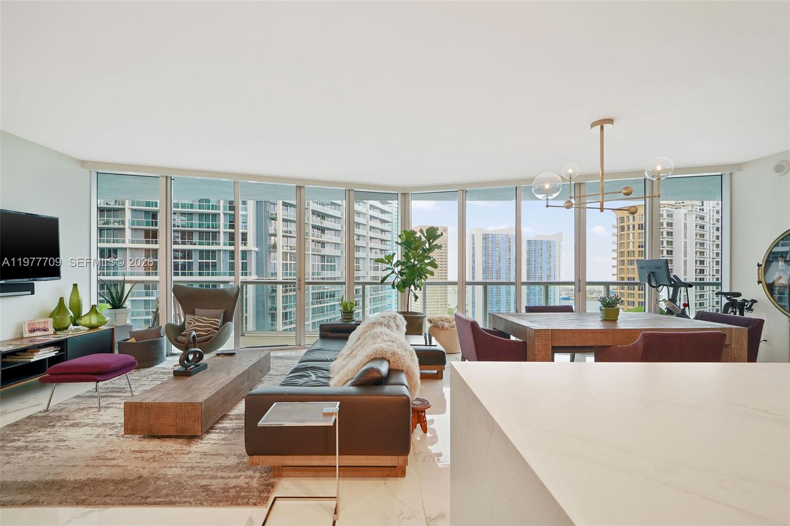 A modern living and dining area features floor-to-ceiling windows with views of city skyscrapers — 495 Brickell Ave # 2804, Miami FL 33131, MIAMI, FL