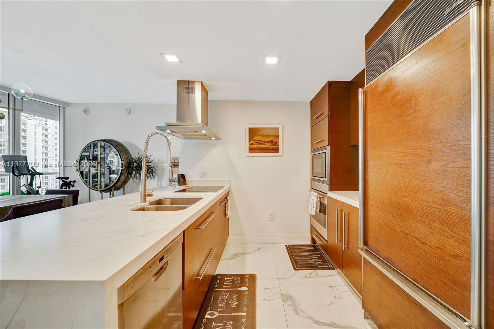 A modern kitchen features wood-toned cabinetry, white marble countertops, and stainless steel appliances — 495 Brickell Ave # 2804, Miami FL 33131, MIAMI, FL