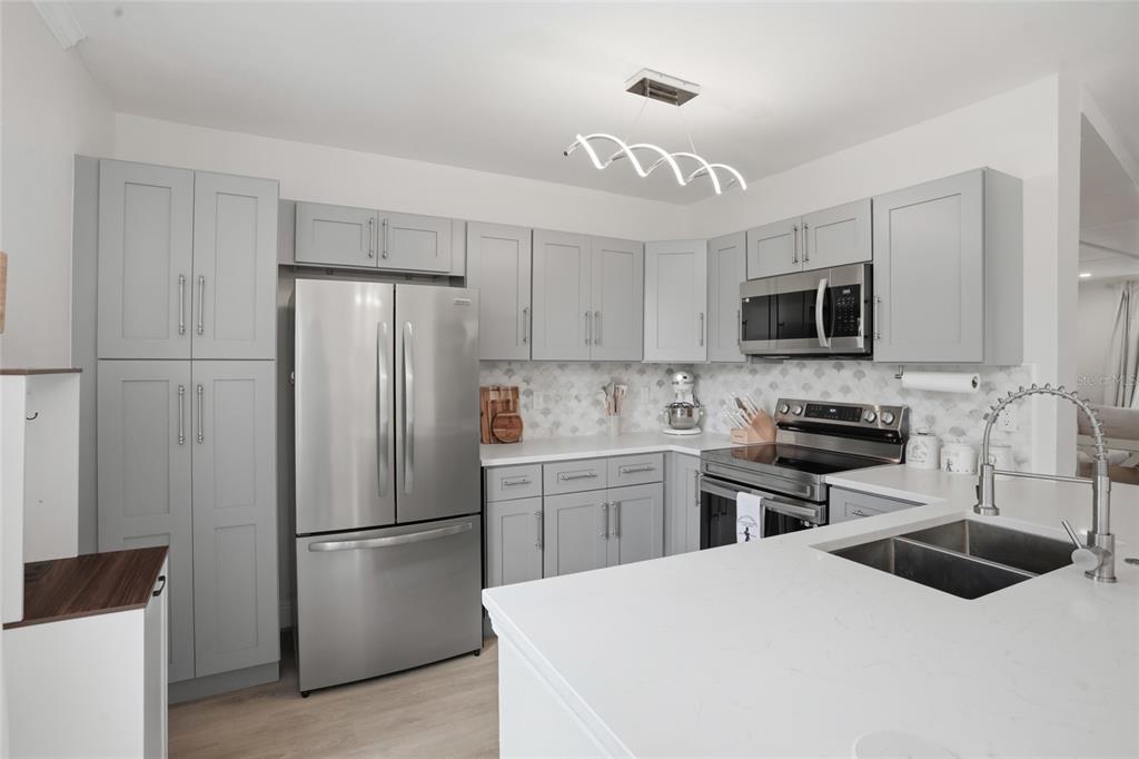 A kitchen with light gray cabinets, stainless steel appliances, and a white quartz countertop island — 1056 WATERSIDE DRIVE, CELEBRATION, FL