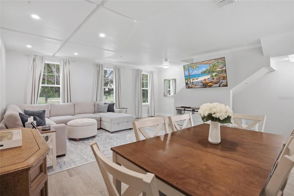 A bright, open-concept living and dining area features white walls, light flooring, and neutral furniture — 1056 WATERSIDE DRIVE, CELEBRATION, FL