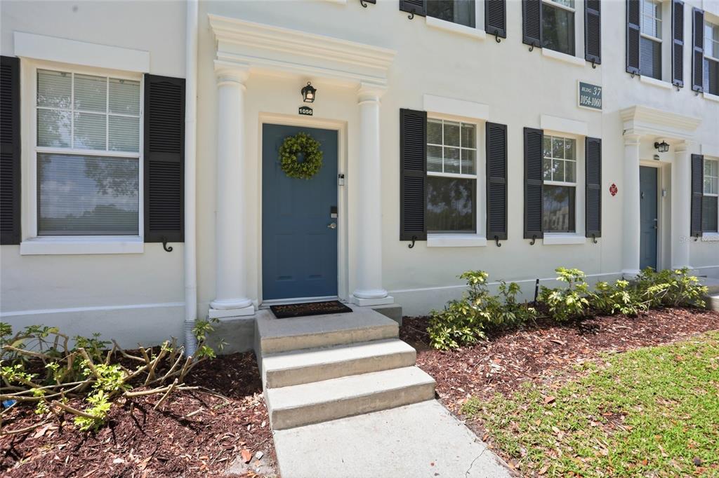 A blue front door with a wreath sits between two windows with black shutters — 1056 WATERSIDE DRIVE, CELEBRATION, FL