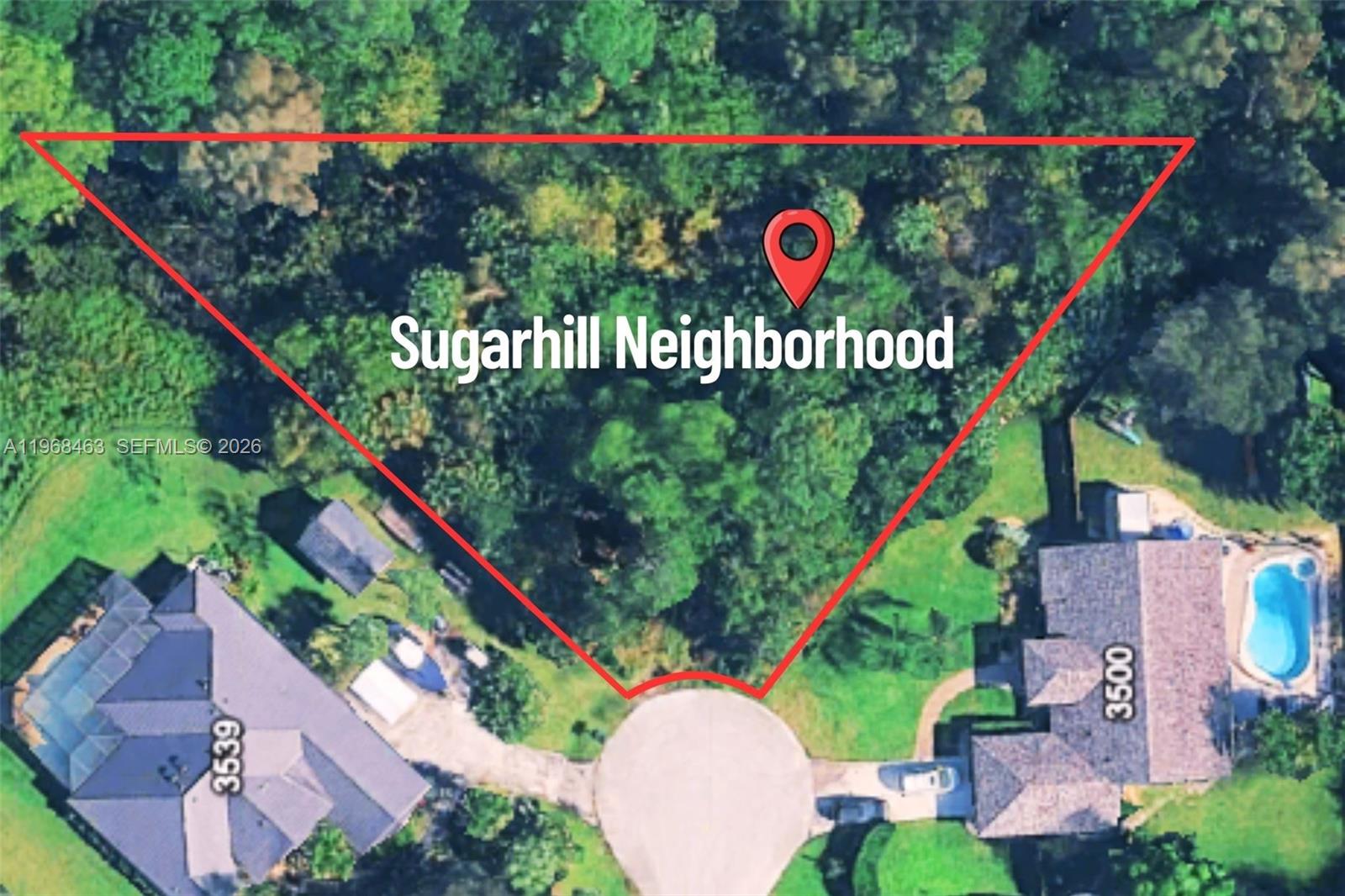An aerial view shows a wooded, triangular-shaped vacant lot situated between two residential properties — 3509 NE M Cari Ln, Jensen Beach FL 34957, JENSEN BEACH, FL