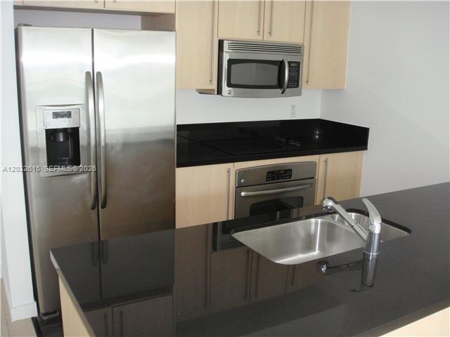 A kitchen features light wood cabinets, stainless steel appliances, and black countertops — 1111 SW 1  AVE, Miami FL 33130, MIAMI, FL