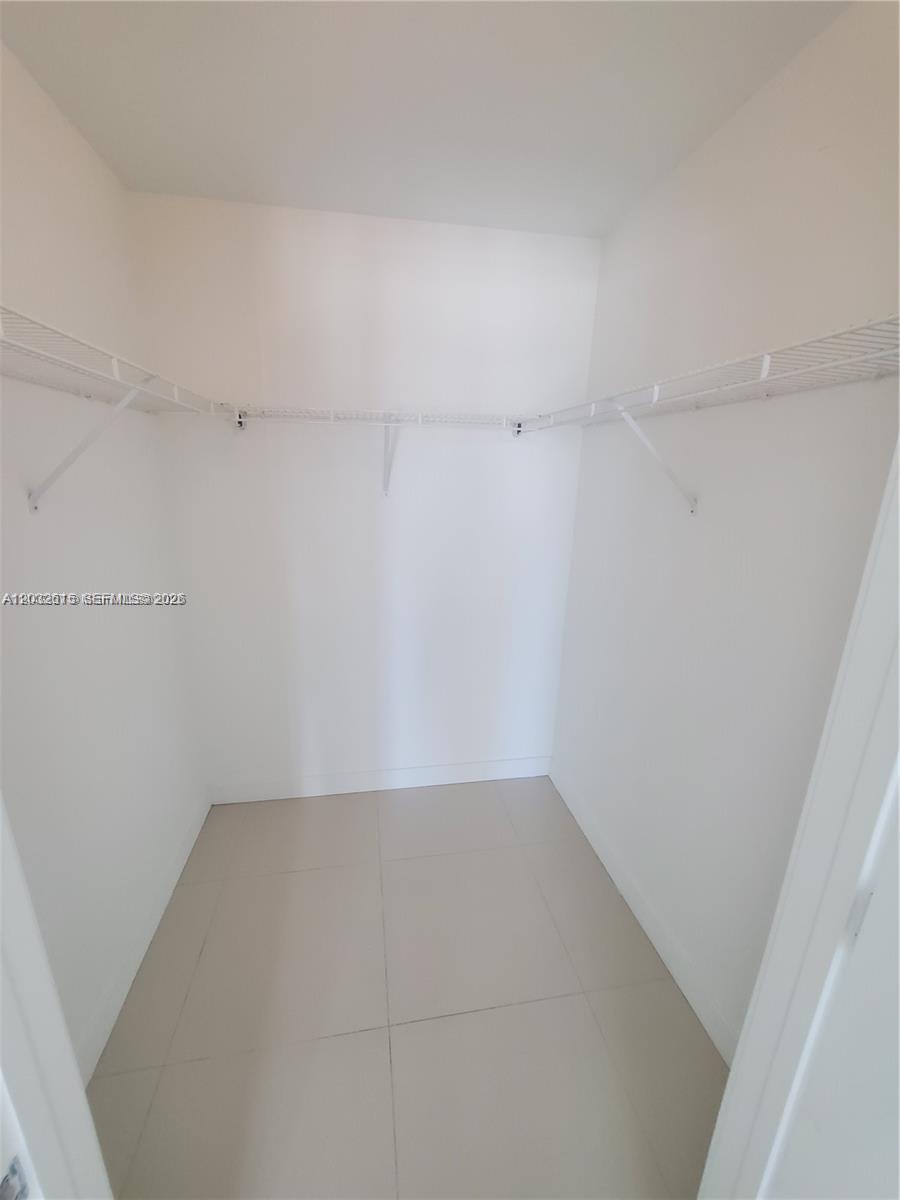 A walk-in closet features white walls, tile flooring, and wire shelving along the walls — 1111 SW 1  AVE, Miami FL 33130, MIAMI, FL