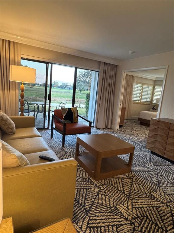 A living room features a sofa, accent chair, coffee table, and sliding doors to a patio — 4786 FOX HUNT DRIVE UNIT D743, WESLEY CHAPEL, FL