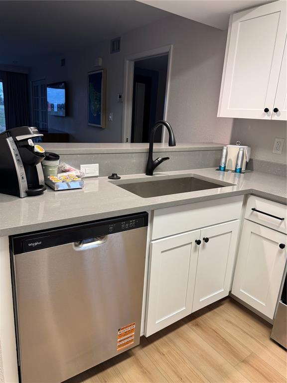 A kitchen features a stainless steel dishwasher, a dark faucet, and white cabinetry — 4786 FOX HUNT DRIVE UNIT D743, WESLEY CHAPEL, FL