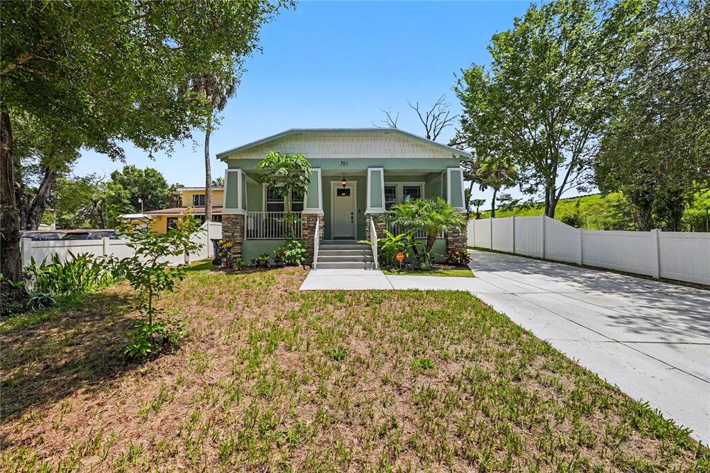 A single-story green house with a front porch, stone accents, and a concrete driveway — 701 E HOLLYWOOD STREET, TAMPA, FL