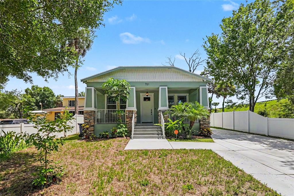 A green bungalow with a front porch, stone accents, and a concrete driveway — 701 E HOLLYWOOD STREET, TAMPA, FL